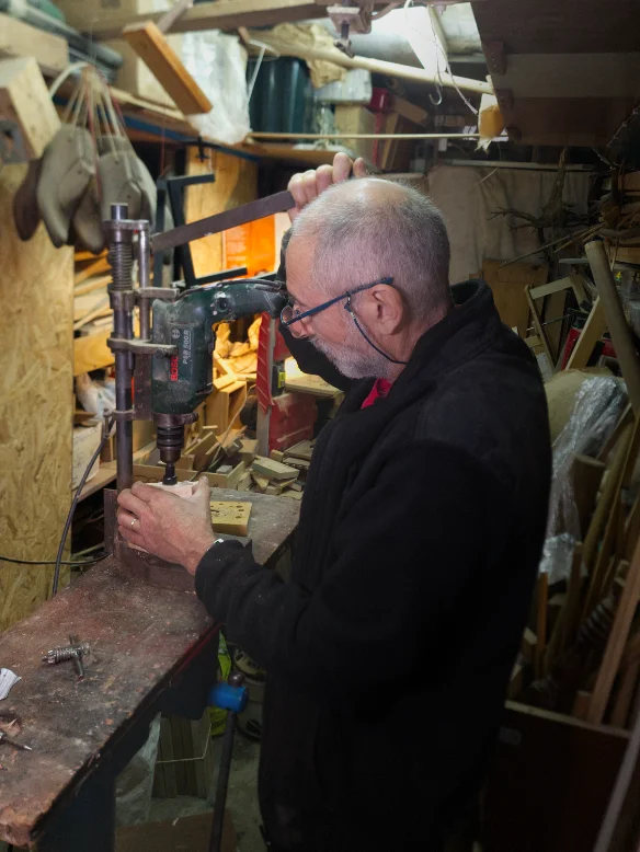 The maker drilling into a small piece of wood at the workbench with a Bosch drill